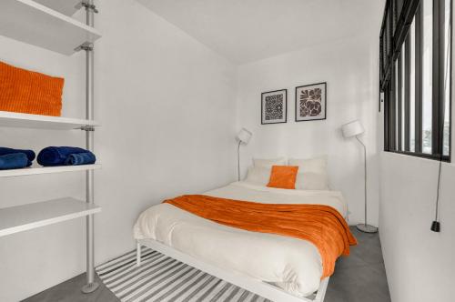 - une chambre blanche avec un lit et une couverture orange dans l'établissement Le Canal Ocre - Netflix - Parking Couvert, à Toulouse