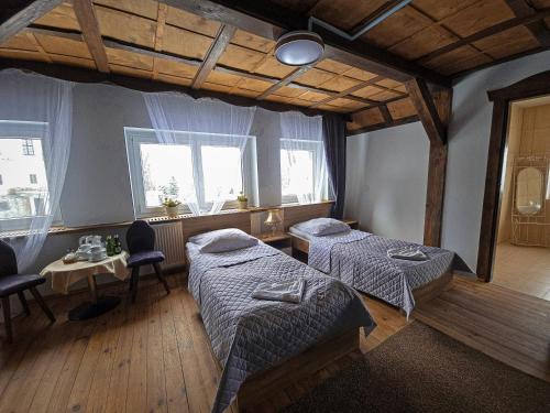 a room with two beds and a table and two windows at Zamek Międzylesie in Międzylesie