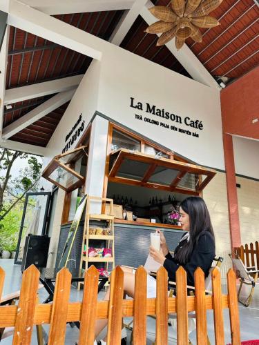 a woman sitting on a bench in front of a cafe at Kolia Resort in Cao Bằng