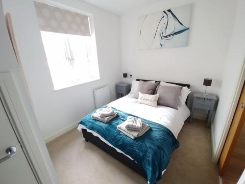 a bedroom with a bed with towels on it at Reigate - Lovely modern serviced apartment in Reigate