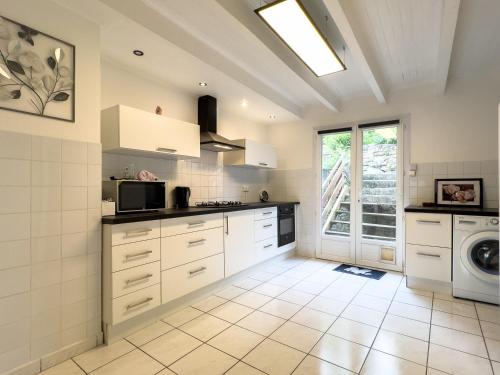 une cuisine avec des armoires blanches et une laveuse et une sécheuse dans l'établissement La Pervenche, à Saint-Julien-du-Gua