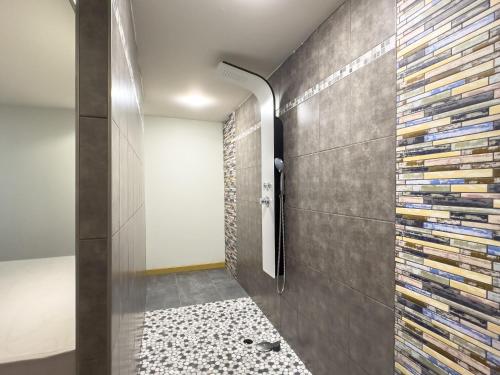 La salle de bains est pourvue d'une douche et d'un mur en pierre. dans l'établissement La Pervenche, à Saint-Julien-du-Gua