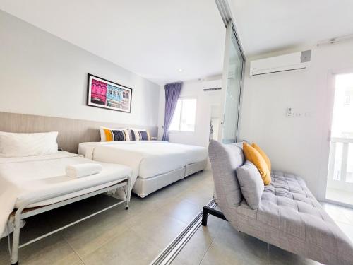a hotel room with two beds and a couch at Recenta Suite Phuket Suanluang in Phuket Town