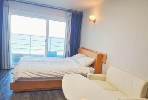 a bedroom with a bed and a couch and a window at Sokcho Accommodation Bada Bom in Sokcho