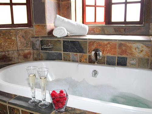 a bath tub with two champagne glasses and roses at Sable Mountain in Hekpoort