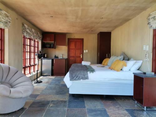 a bedroom with a large white bed and a chair at Sable Mountain in Hekpoort