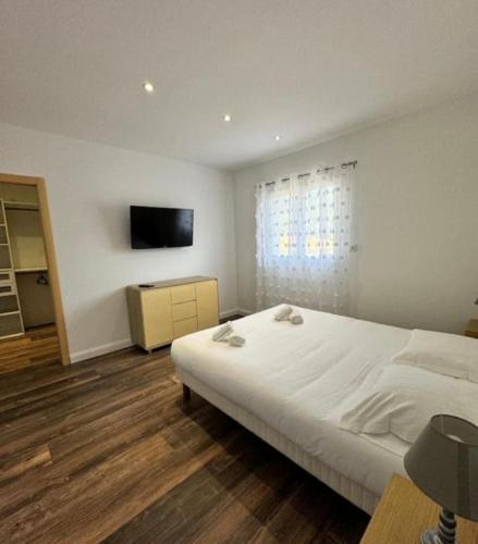 a bedroom with a large white bed and a television at Appartement de standing aux portes de Propriano in Propriano