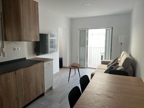 eine Küche und ein Wohnzimmer mit einer Couch und einem Tisch in der Unterkunft Piso céntrico en Conil de la Frontera in Conil de la Frontera