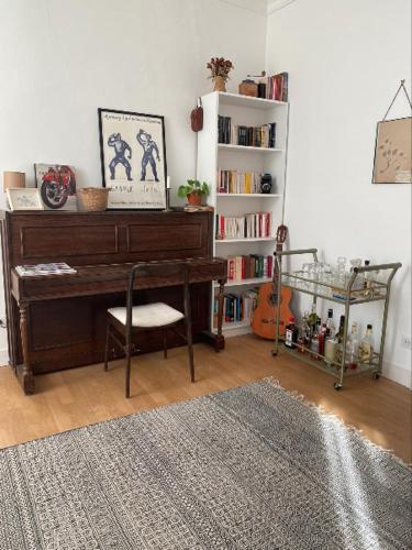 a living room with a piano and a book shelf at La Maison des Ifs Paon in Mamers