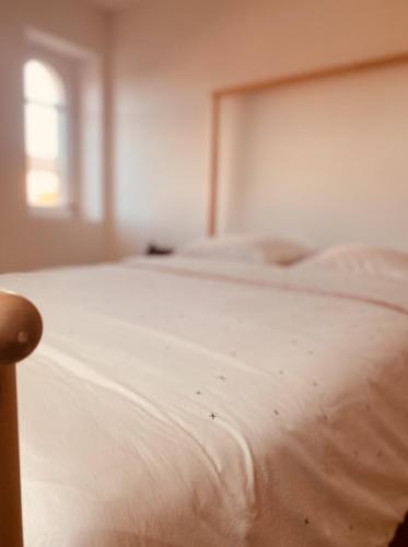a white bed in a bedroom with a window at La Maison des Ifs Paon in Mamers