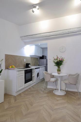 une cuisine avec des armoires blanches et une table et des chaises dans l'établissement Superbe appartement & proche mer, à Nice