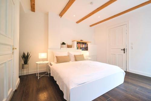 a white bedroom with a large white bed and wooden floors at Ferienwohnung Villa Wagersrott in Wagersrott