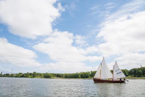 a boat with white sails in the water at Ferienwohnung Villa Wagersrott in Wagersrott