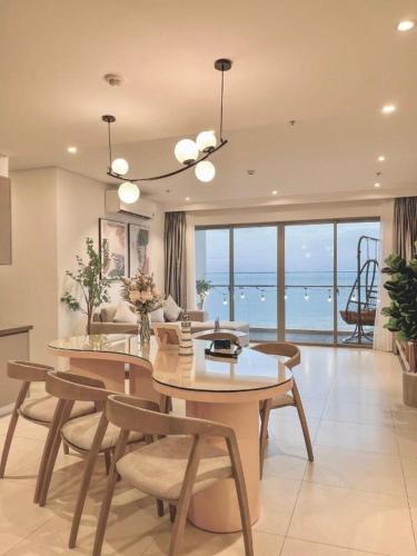 a living room with a table and chairs and the ocean at Erica's House - Oceanview The Sóng Apartment Vũng Tàu Nghỉ Dưỡng Biển Cao Cấp 5 Sao - The Song Vung Tau Condotel 5 Star Beach View Apartment in Vung Tau