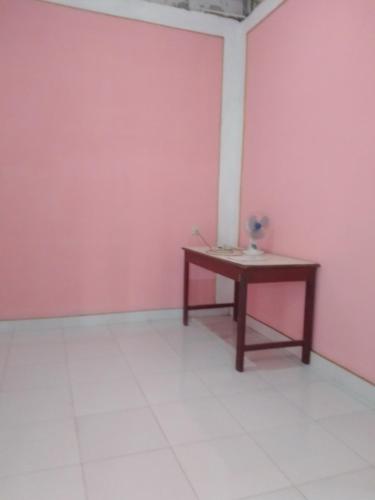 a room with a table and a pink wall at De Ikut Bojo Homestay Prambanan Breksi in Kenaran