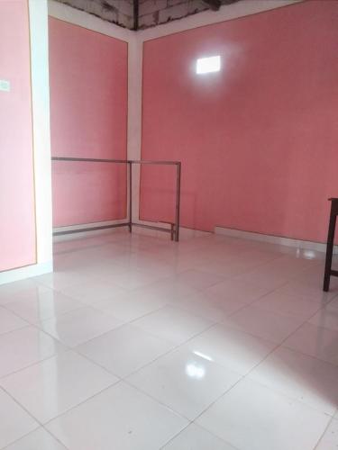an empty room with red walls and white floors at De Ikut Bojo Homestay Prambanan Breksi in Kenaran