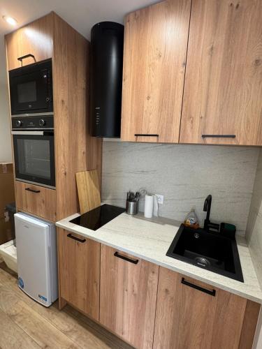 La cuisine est équipée de placards en bois, d'un évier et d'un four micro-ondes. dans l'établissement Quiet accommodation near train station, à Saint-Mammès
