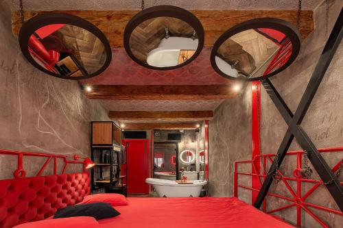 a bedroom with a red bed and two round mirrors at Masoch. Hotel & Cafe in Lviv