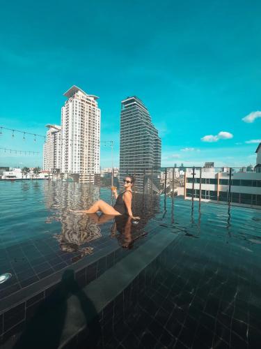 eine Frau, die im Wasser in einem Schwimmbecken liegt in der Unterkunft De Prime Rangnam Hotel in Bangkok