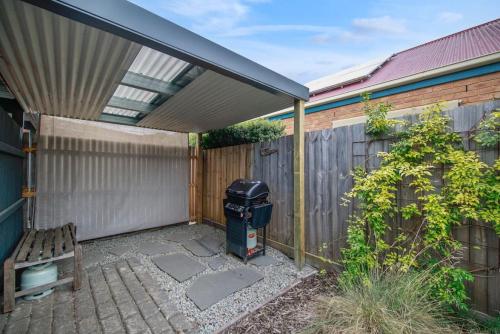 a patio with a trash can and a fence at Little Gem in Ocean Grove