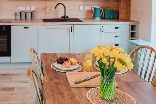 a kitchen with a wooden table with yellow flowers on it at Old Kyle Farm - Stunning Views - 2 mins from Skye Bridge in Kyleakin