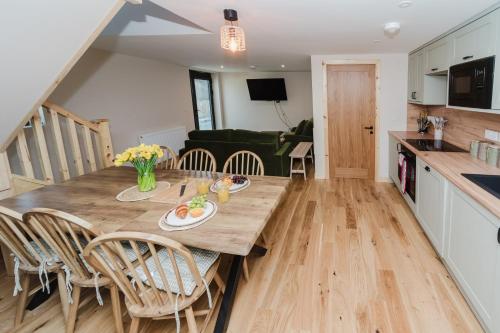 a kitchen and living room with a wooden table and chairs at Old Kyle Farm - Stunning Views - 2 mins from Skye Bridge in Kyleakin