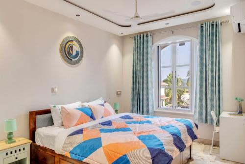 a bedroom with a bed and a window at Aqua 2 BHK Apartment by tisyastays in Candolim
