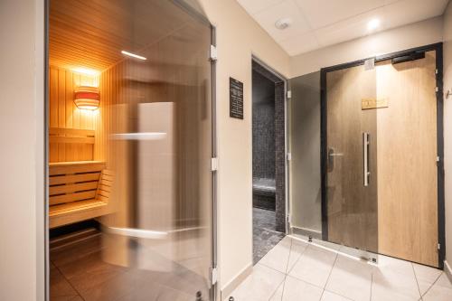 a walk in shower with a glass door in a bathroom at Résidence Club MMV Le Silvana in Risoul