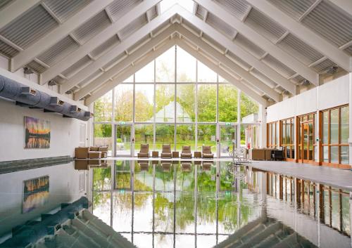 Cette grande chambre dispose d'une grande fenêtre et d'une piscine d'eau. dans l'établissement NEW Squirrels Leap Lake Views with Spa Access, à Somerford Keynes