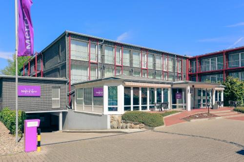 a building with a purple sign in front of it at Mercure Hotel am Entenfang Hannover in Hannover