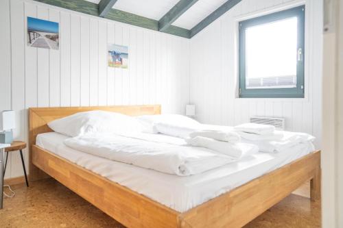 a bedroom with a bed with white sheets and a window at Hol(t)z Hus in Born