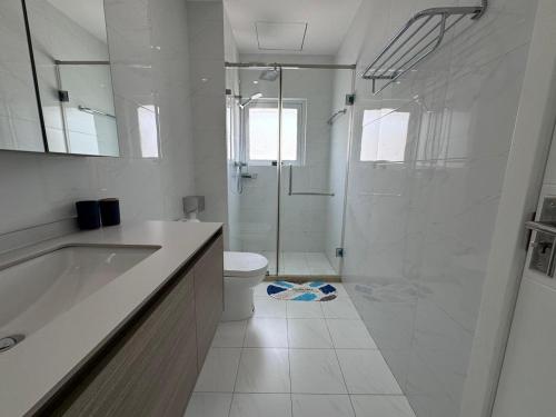 a white bathroom with a shower and a toilet at Luxury Escape Spacious Stay with Pool and Terrace in Luanda