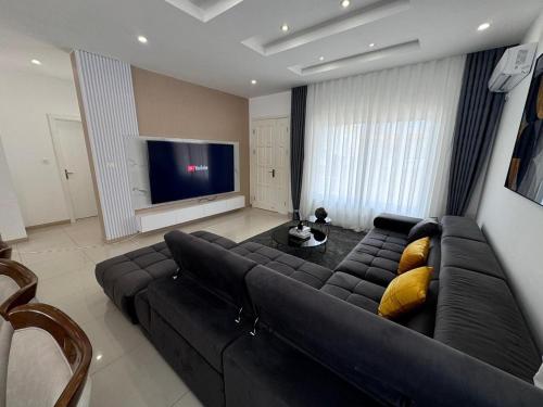 a living room with a black couch and a television at Luxury Escape Spacious Stay with Pool and Terrace in Luanda