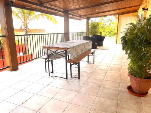 a patio with a table and bench on a porch at Tissianna Villa Confort de Grand Anse in Petite Île