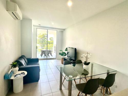 a living room with a blue couch and a glass table at 2 Bedroom aparment with Views and parking in Garden City in Brisbane