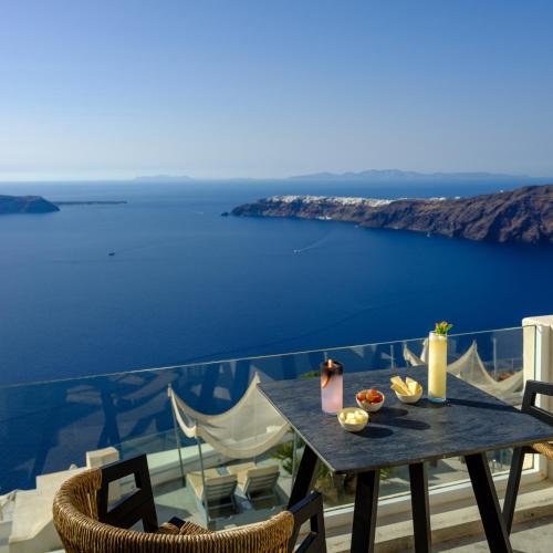 a table on a balcony with a view of the ocean at Andromeda Villas & Spa Resort in Imerovigli