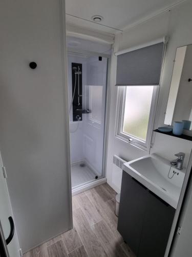 - une cuisine blanche avec un évier et une douche dans l'établissement Mobilhome dans Camping Vias plage, à Vias