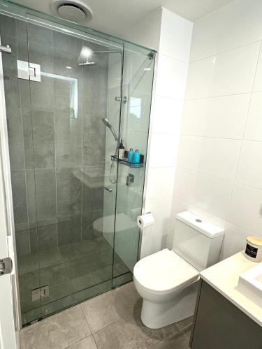 a bathroom with a toilet and a glass shower at 2 Bedroom aparment with Views and parking in Garden City in Brisbane