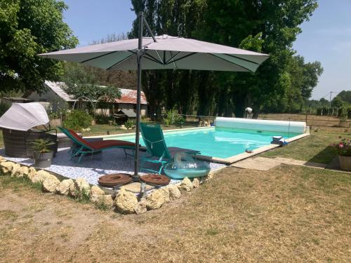 - une piscine avec 2 chaises et un parasol dans l'établissement Maison avec piscine dans airial Landais, à Cudos