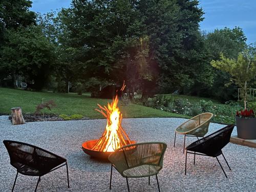 a fire pit in a yard with three chairs at Les Arches du Lac, spa et piscine intérieure chauffée in Saint-Martin-lès-Langres