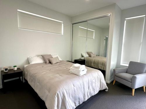 a bedroom with a bed and a chair and a mirror at 2 Bedroom aparment with Views and parking in Garden City in Brisbane