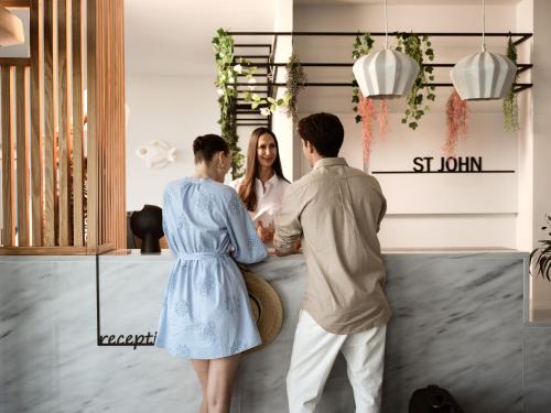 a group of three people standing around a woman at Hotel St John Villas in Tsilivi