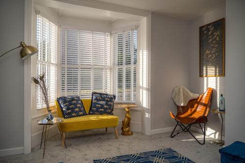 a living room with a yellow couch and a chair at Lovely house on Trinity Square, edge of Old Town in Margate