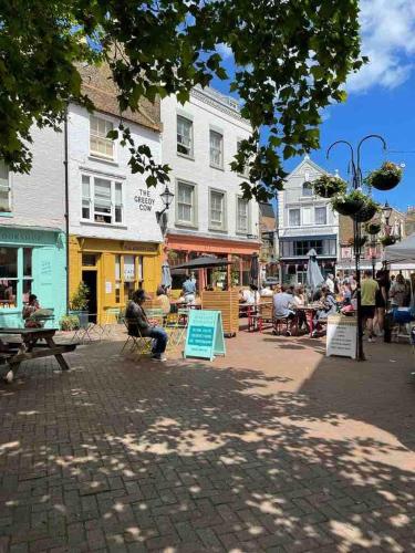 a group of people sitting at tables on a city street at Lovely house on Trinity Square, edge of Old Town in Margate