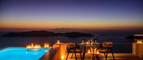 a restaurant with a view of the ocean at night at Andromeda Villas & Spa Resort in Imerovigli