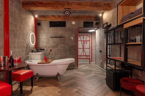 a bathroom with a white tub and a red door at Masoch. Hotel & Cafe in Lviv