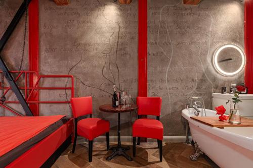a bathroom with red chairs and a sink and a tub at Masoch. Hotel & Cafe in Lviv