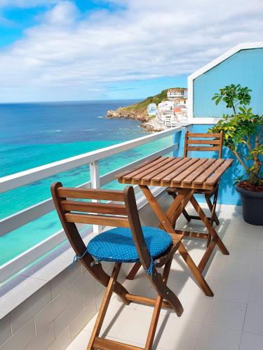 a wooden table and chairs on a balcony with the ocean at AG Apartamento Nordés Malpica primera línea playa in Malpica