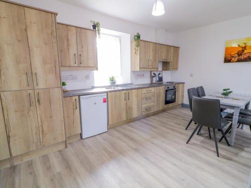 a kitchen with wooden cabinets and a dining table at Town House No 1 in Falcarragh