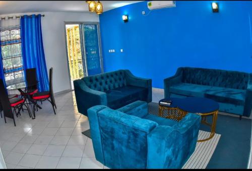 a blue room with couches and a table and chairs at Black Diamond Appartements in Kribi